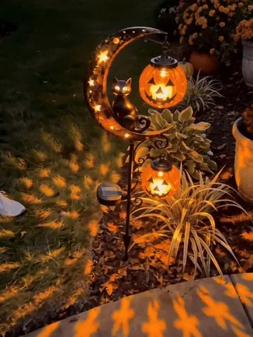 Solar pumpkin moon garden stake glowing beside a path after dark