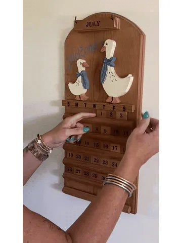 Hands rearranging the date tiles on a wooden perpetual calendar