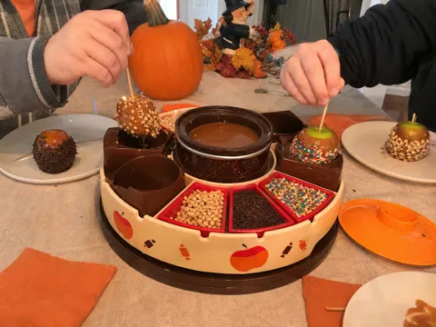 Family decorating caramel apples at a fall gathering