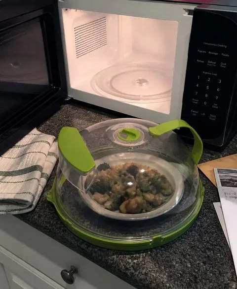 Splatter cover beside a clean open microwave