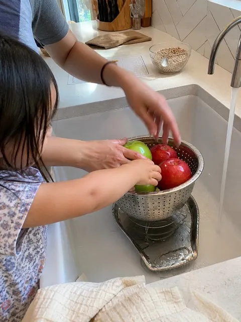 Parent and child washing apples in the colander