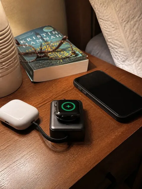 Compact 3-in-1 charger with everyday devices on a bedroom nightstand