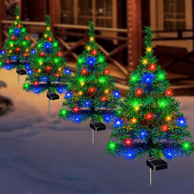 Four solar Christmas tree lights lighting up a snowy path