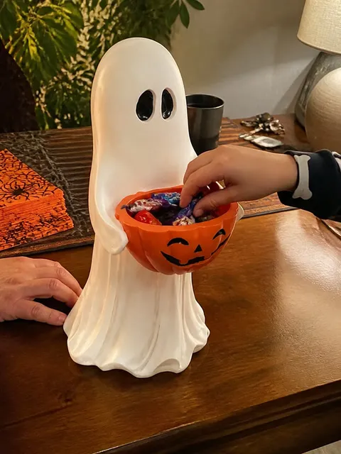 Ghost pumpkin bowl holding candy at a family table