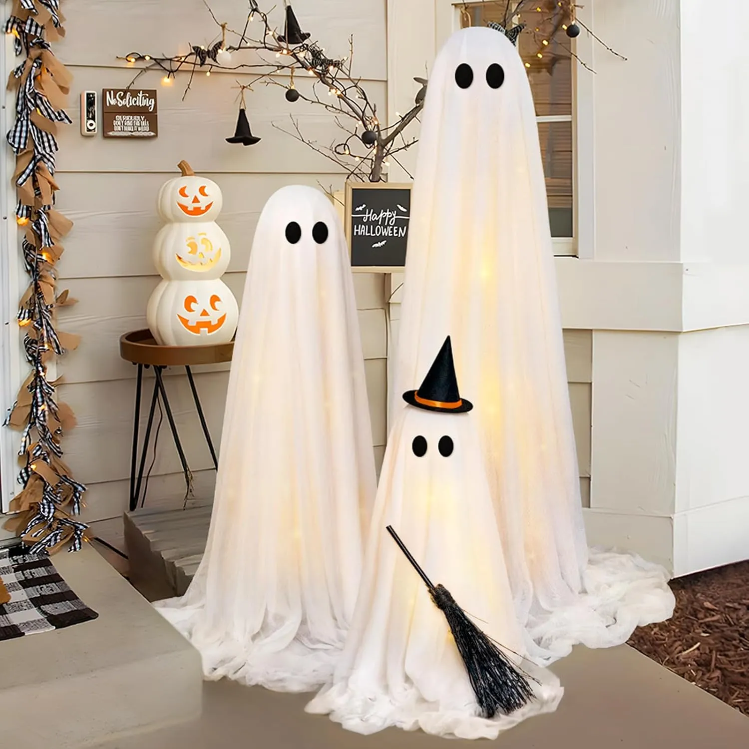 Three warm glowing white ghosts decorating a covered porch