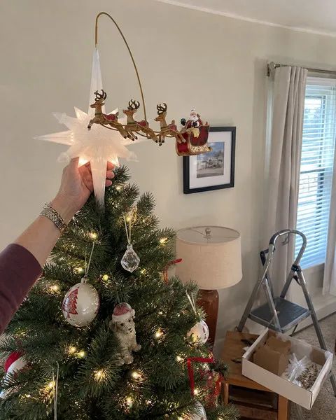 Tree topper being adjusted in a daytime living room