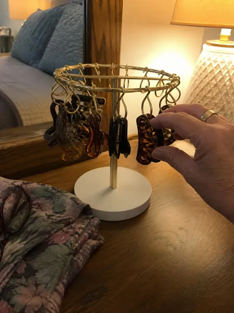 Gold-tone organizer holding dark claw clips on a wood dresser