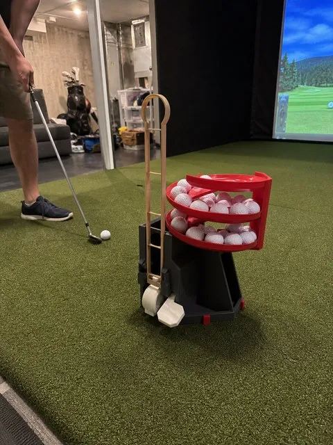 Golf ball dispenser beside a basement simulator mat