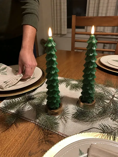 Customer-style photo of two tree candles on a dinner table