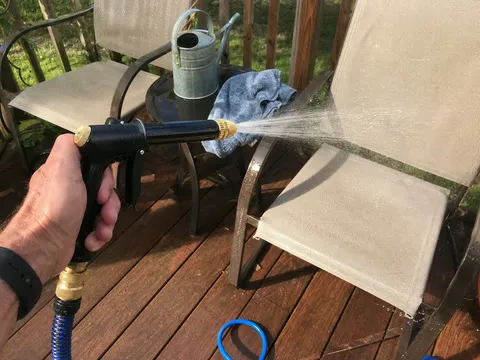 Patio chairs being rinsed with the adjustable black and brass sprayer