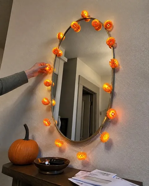 Marigold flower string lights arranged around an entryway mirror