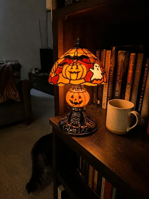 Glowing pumpkin lamp on a lived-in bookshelf