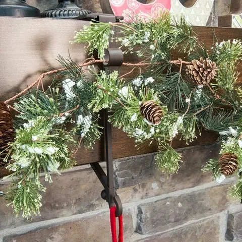 Black hanger supporting garland on a dark wood mantel
