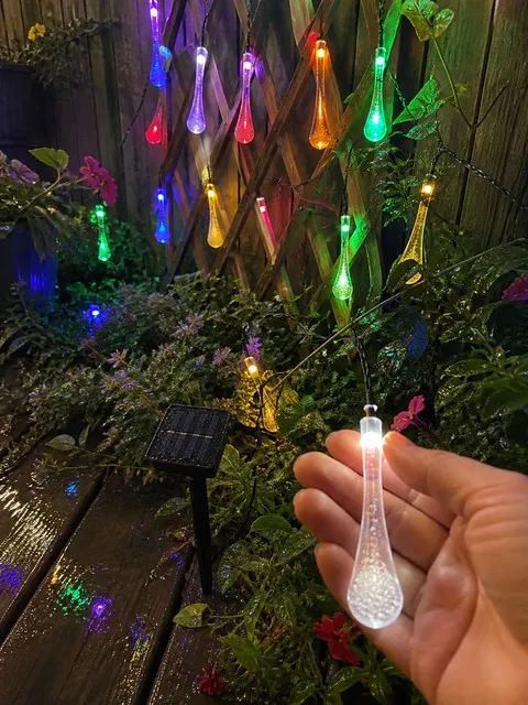 Glowing solar waterdrop lights in a garden after rain