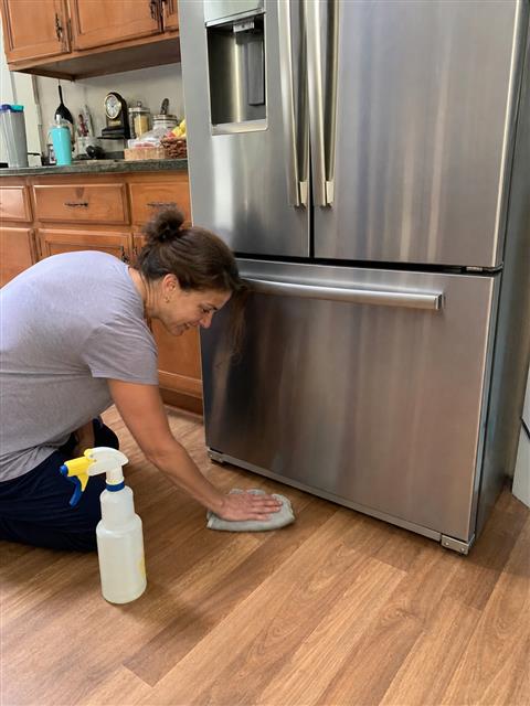 Cleaning the floor beside a refrigerator on appliance rails