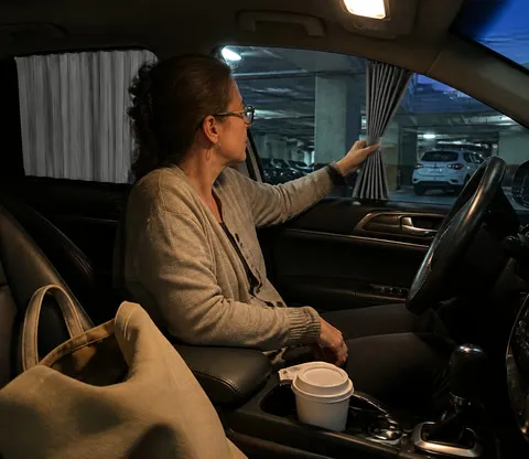 Commuter using a car window curtain during a parked break