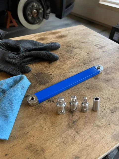 Blue offset extension wrench and four adapters on a garage workbench
